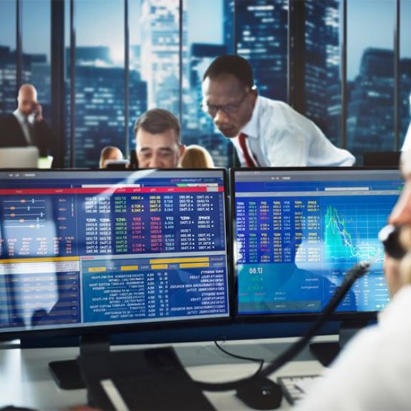 Team on the trading floor with a man looking at a computer screen.
